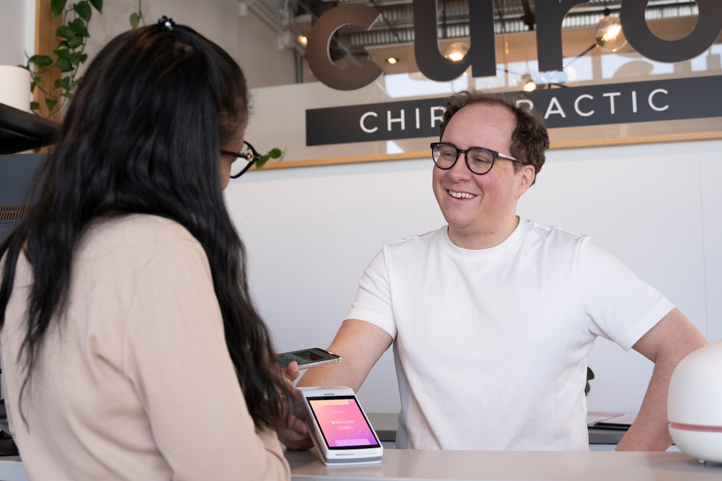 Service professional smiles while assisting customer with payment.